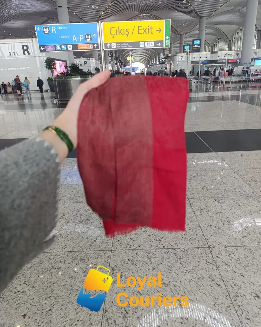 Gidiş salonunda elde tutulan kırmızı bir atkı.