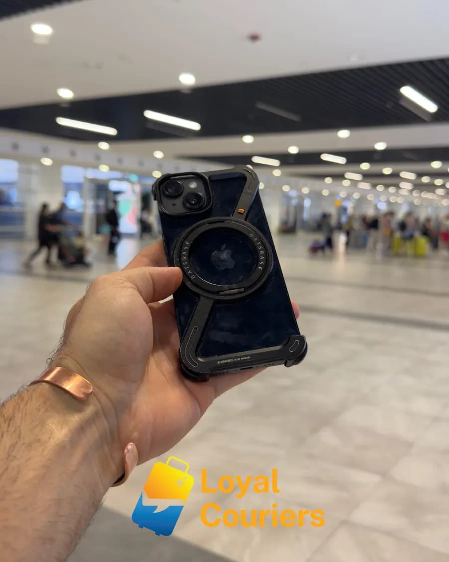 Geliş salonunda elde tutulan dayanıklı kılıflı bir telefon.
