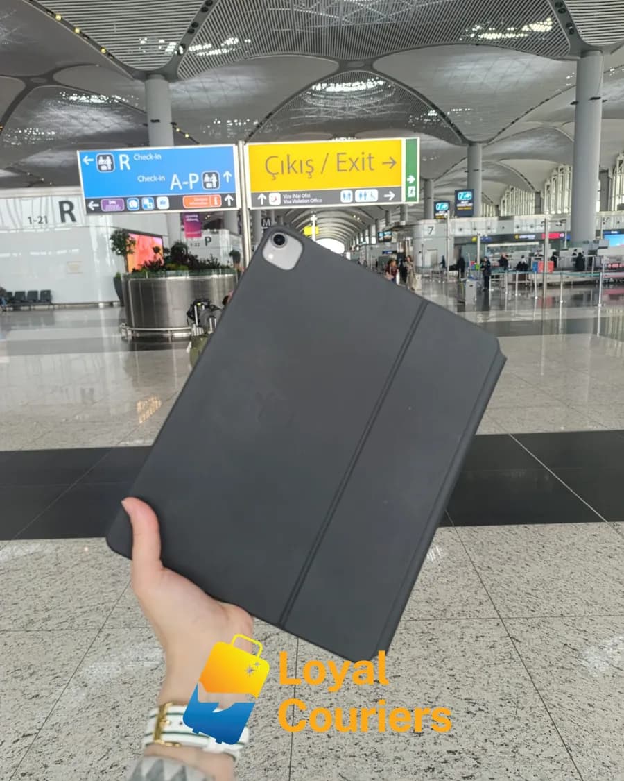 Gidiş salonunda elde tutulan koyu kılıflı bir tablet.