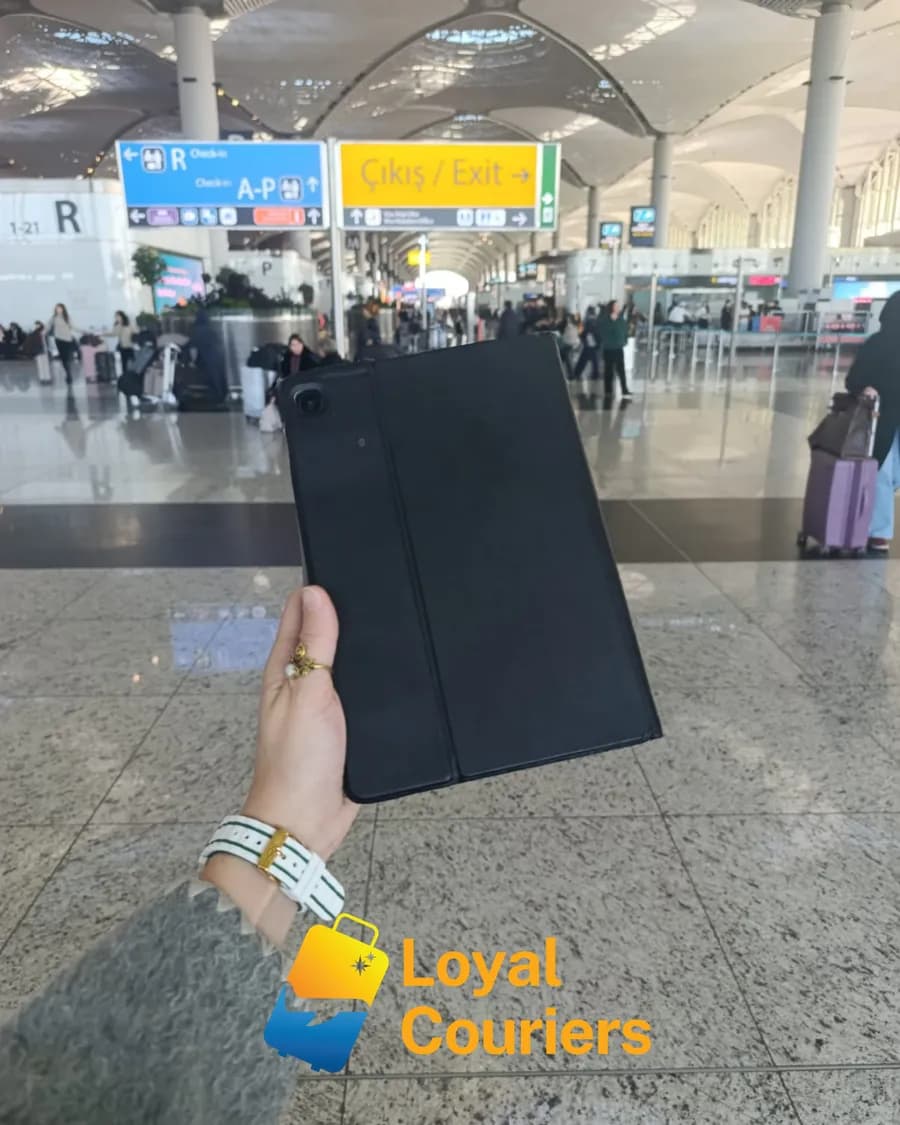 Gidiş salonunda elde tutulan koyu kapaklı kılıflı bir tablet.