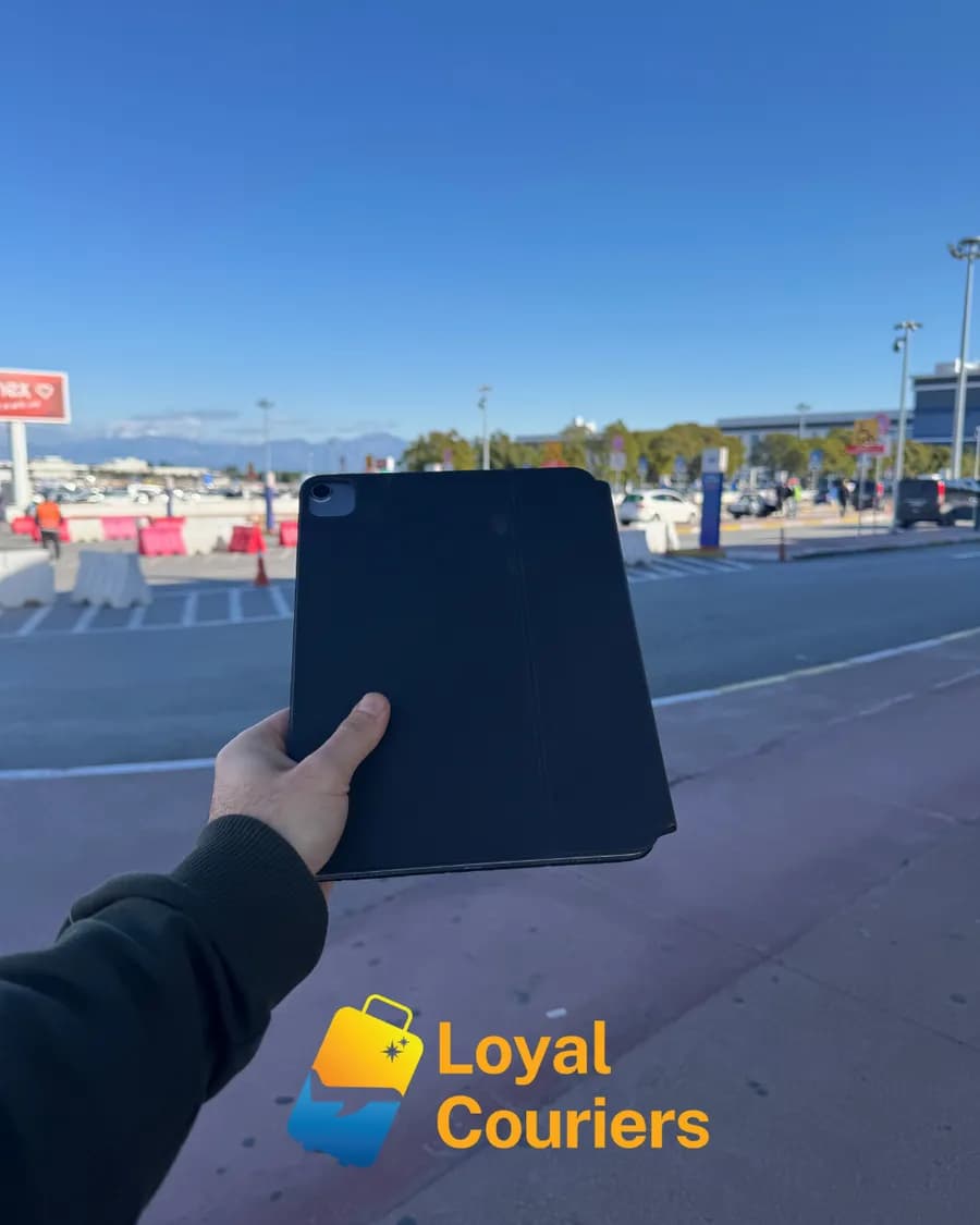Terminal dışında açık gökyüzü altında elde tutulan siyah kılıflı bir tablet.