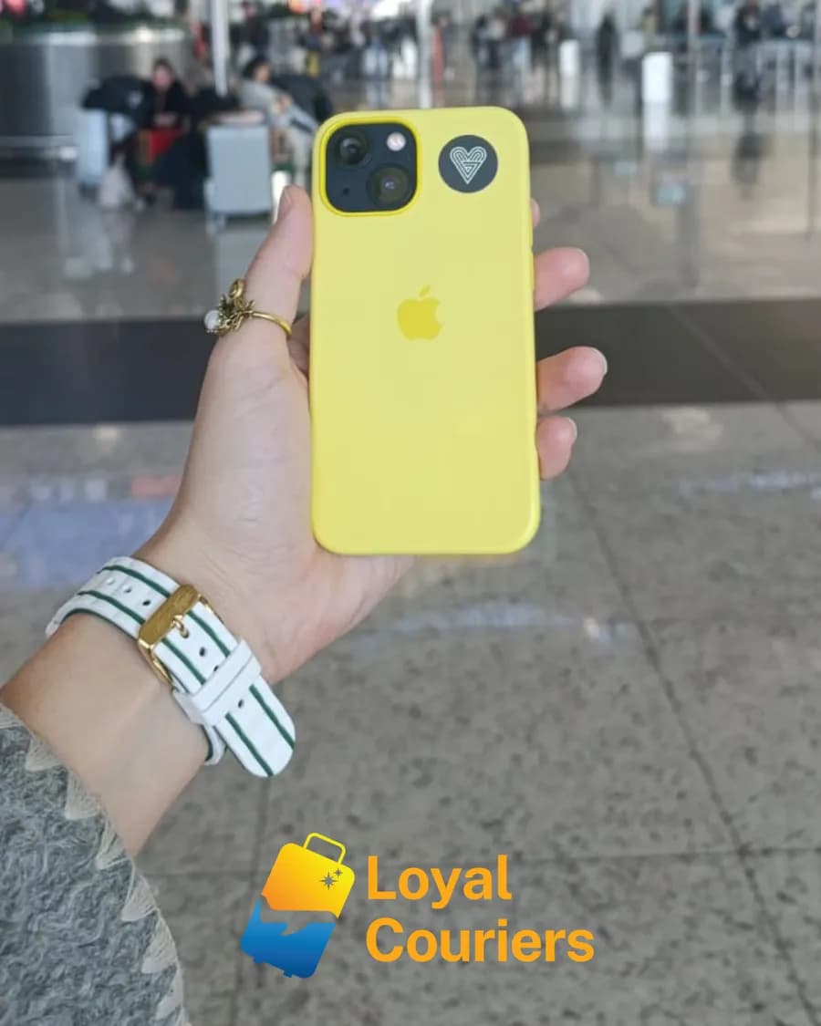 Terminalde elde tutulan sarı bir telefon.